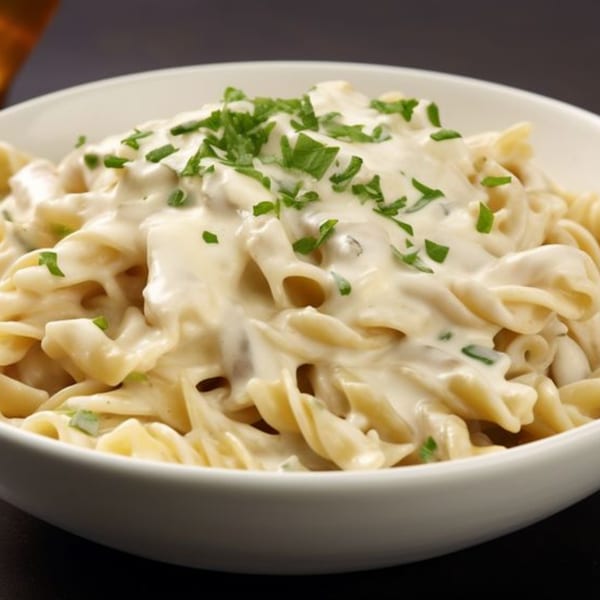 Z Pastabar's creamy pasta dish, topped with fresh green herbs, served in a white bowl.